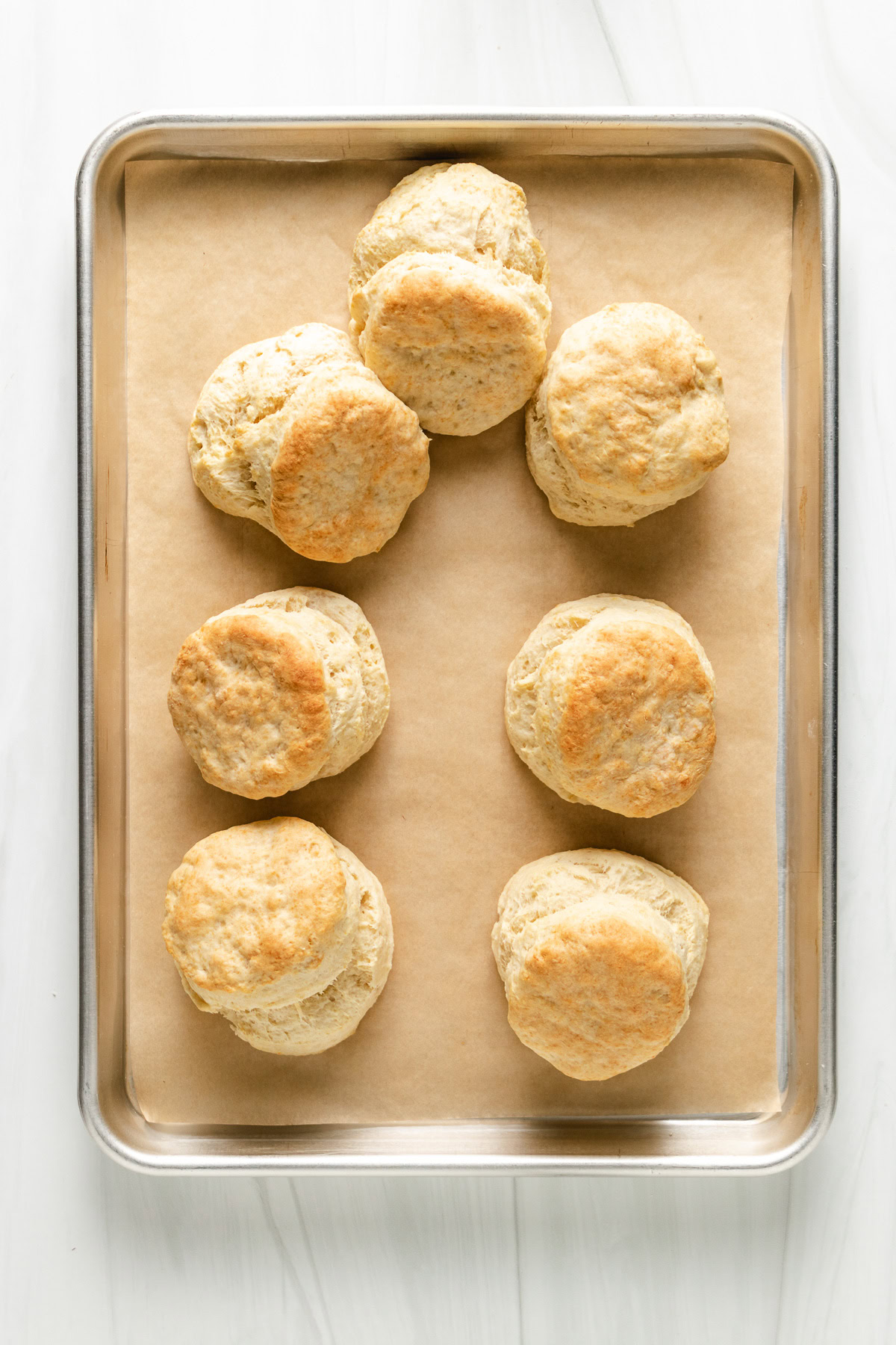 Freshly baked sourdough biscuits on a baking sheet.