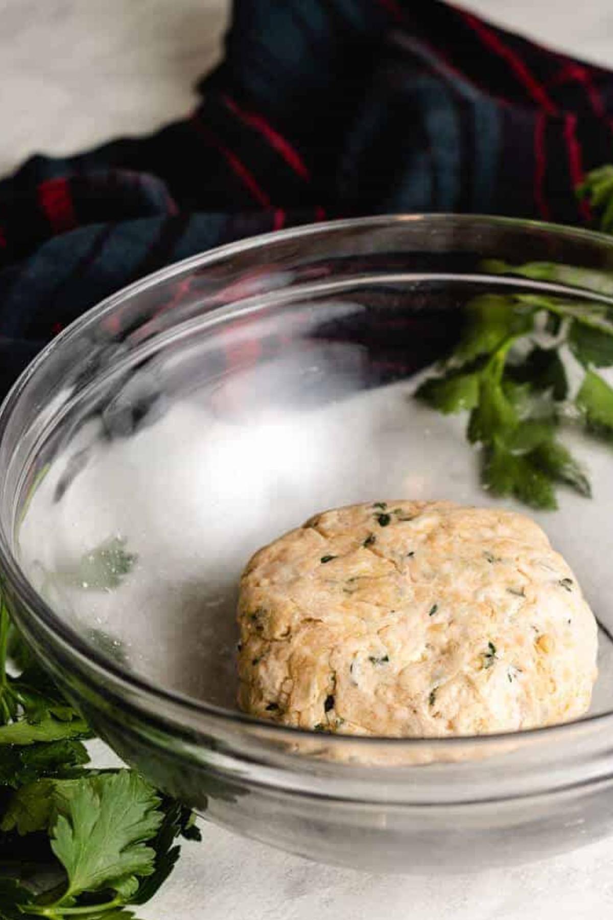 Ball of sourdough parmesan cracker dough in a glass bowl.