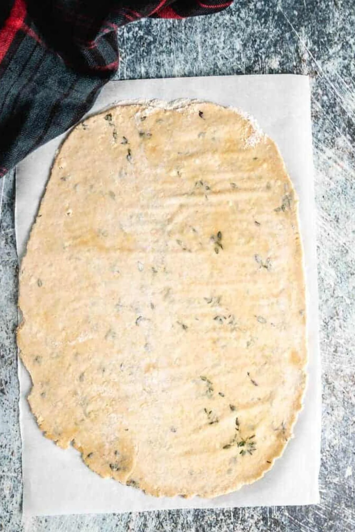 Sourdough parmesan cracker dough rolled out on parchment.