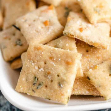 Close up view of parmesan sourdough crackers on a white platter.