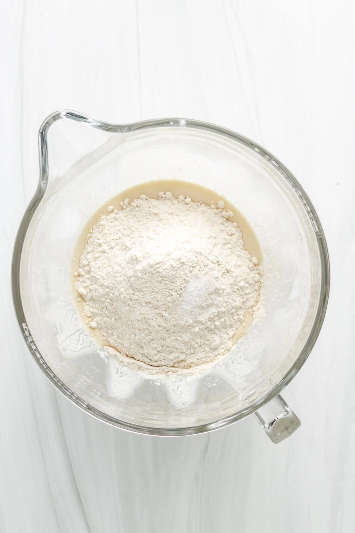 Flour and salt added to a bowl to make naan bread.
