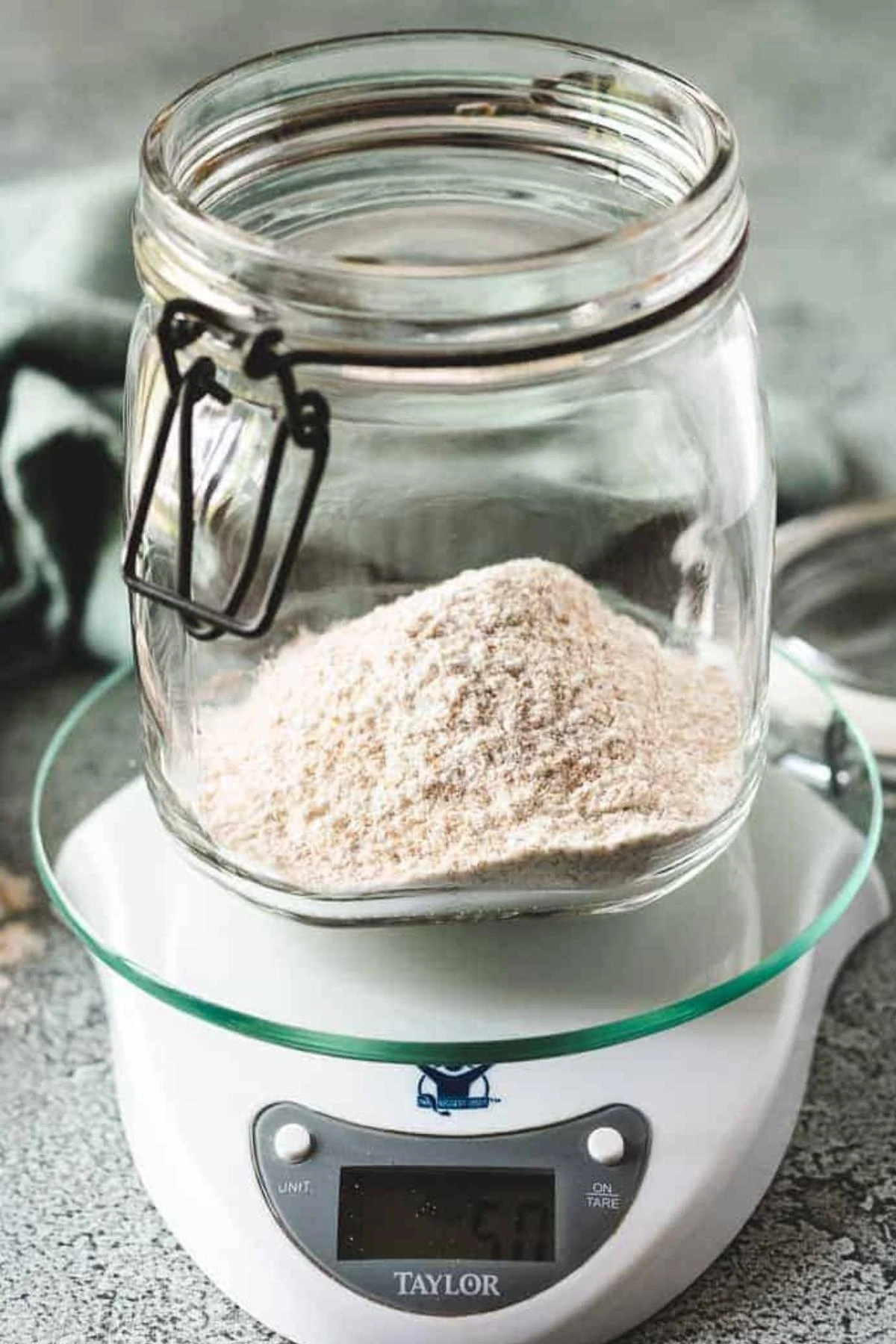 Whole wheat flour measured in a glass jar on a kitchen scale for sourdough starter.