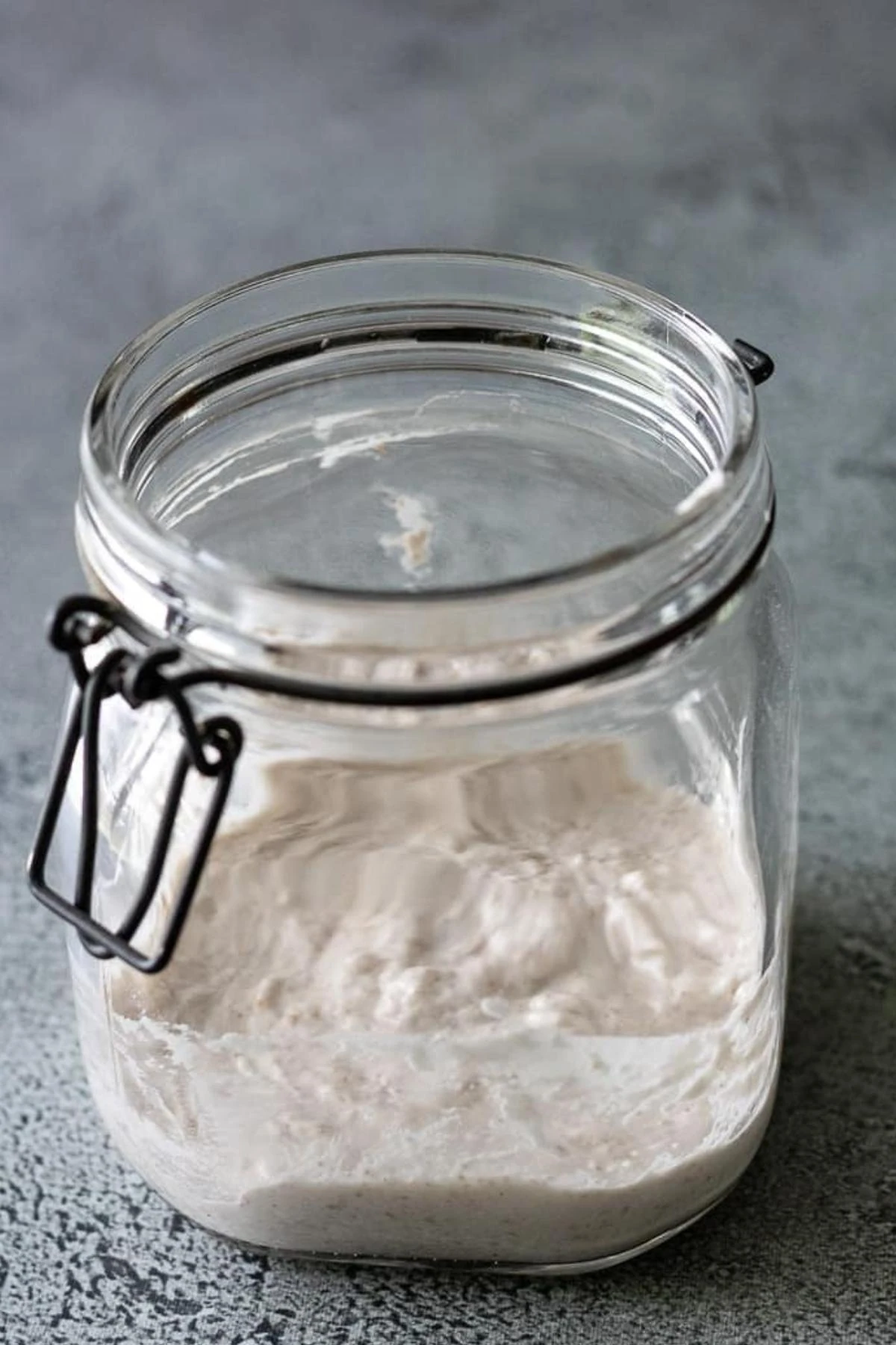 Active sourdough starter rising in a glass jar.