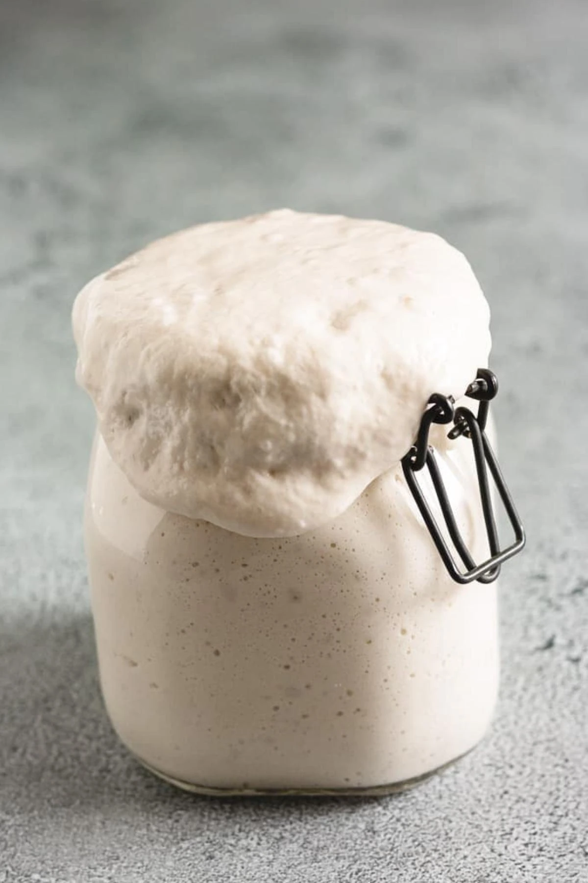 Active sourdough starter in a glass jar with bubbles along the side.