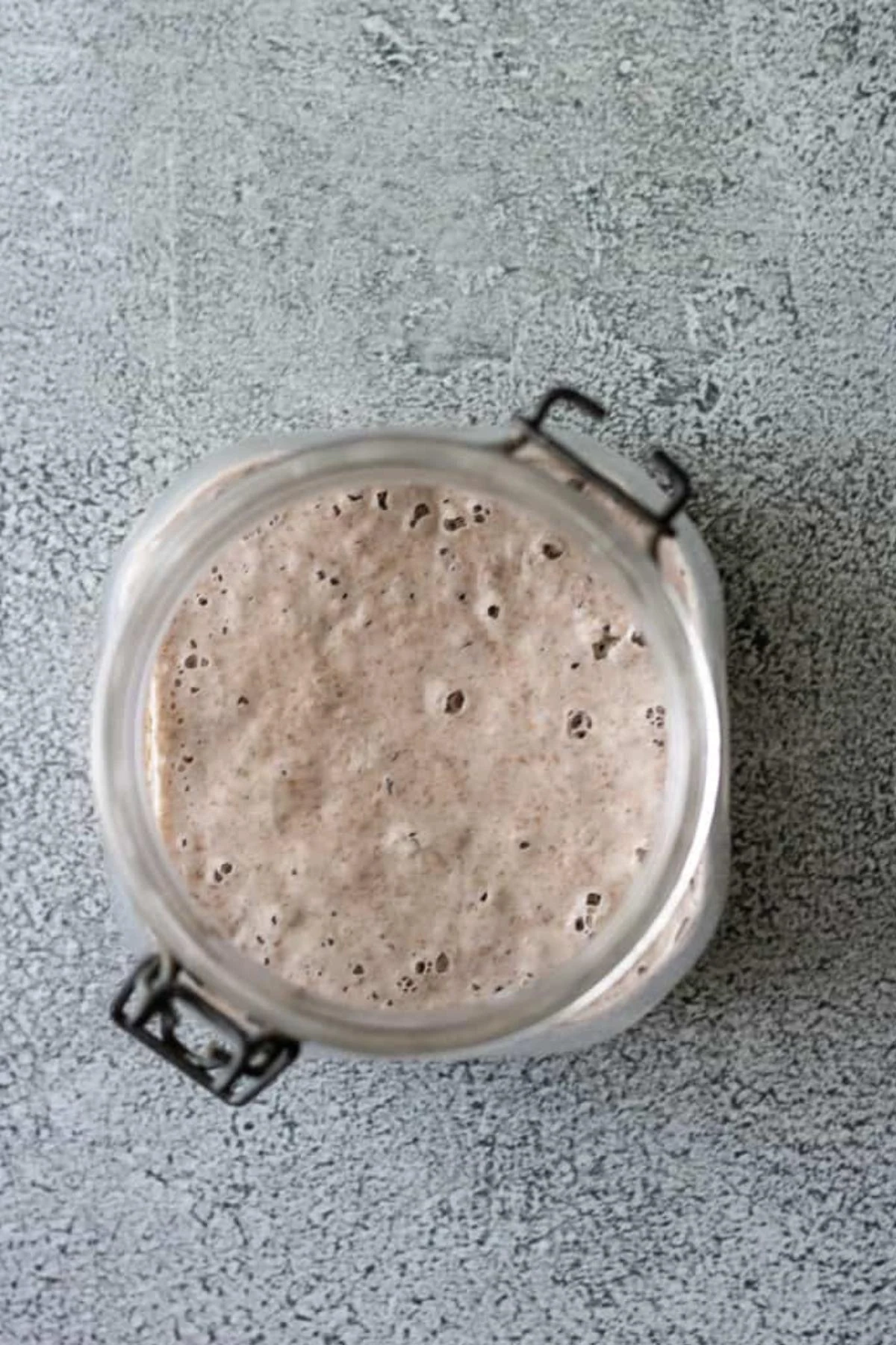 Bubbly sourdough starter viewed from the top of a glass jar.