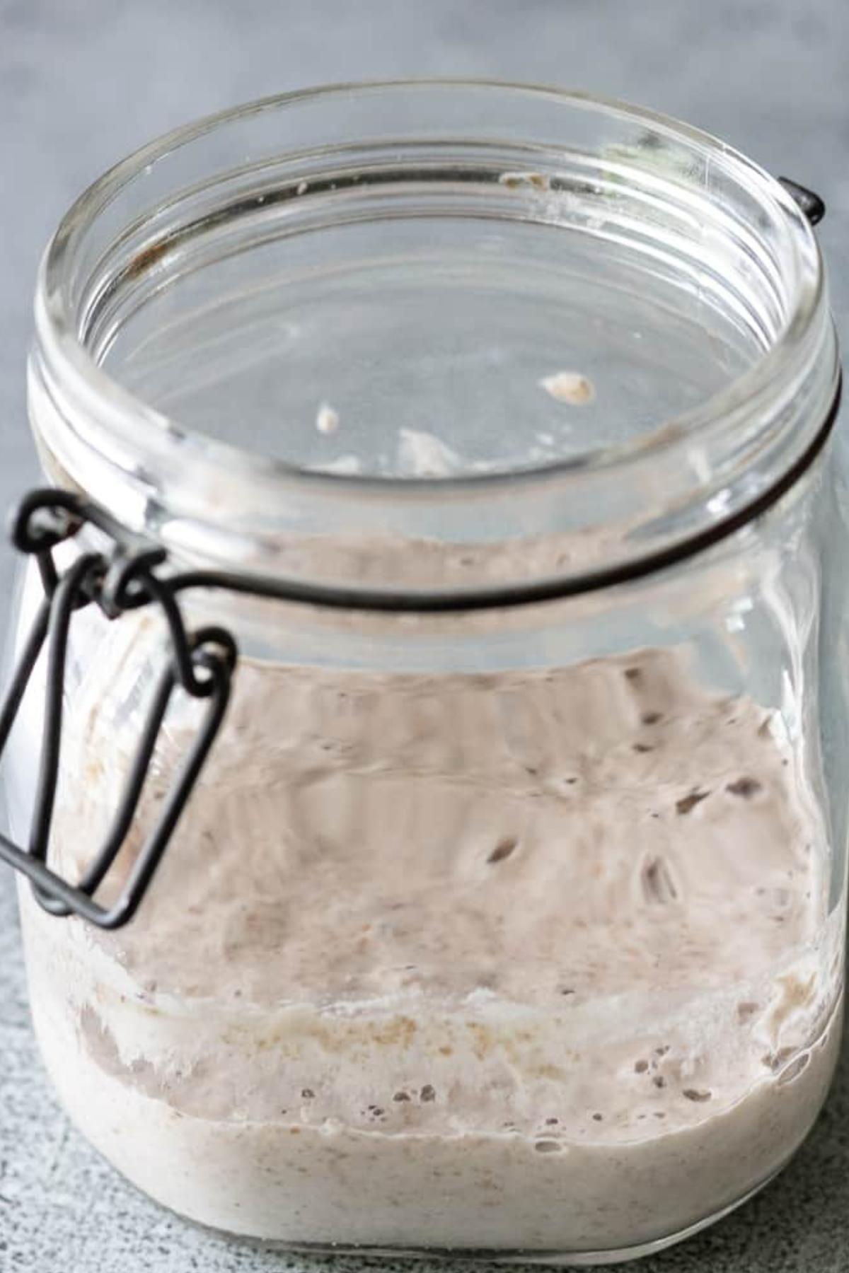 Close up of sourdough starter with small bubbles visible through the glass jar.