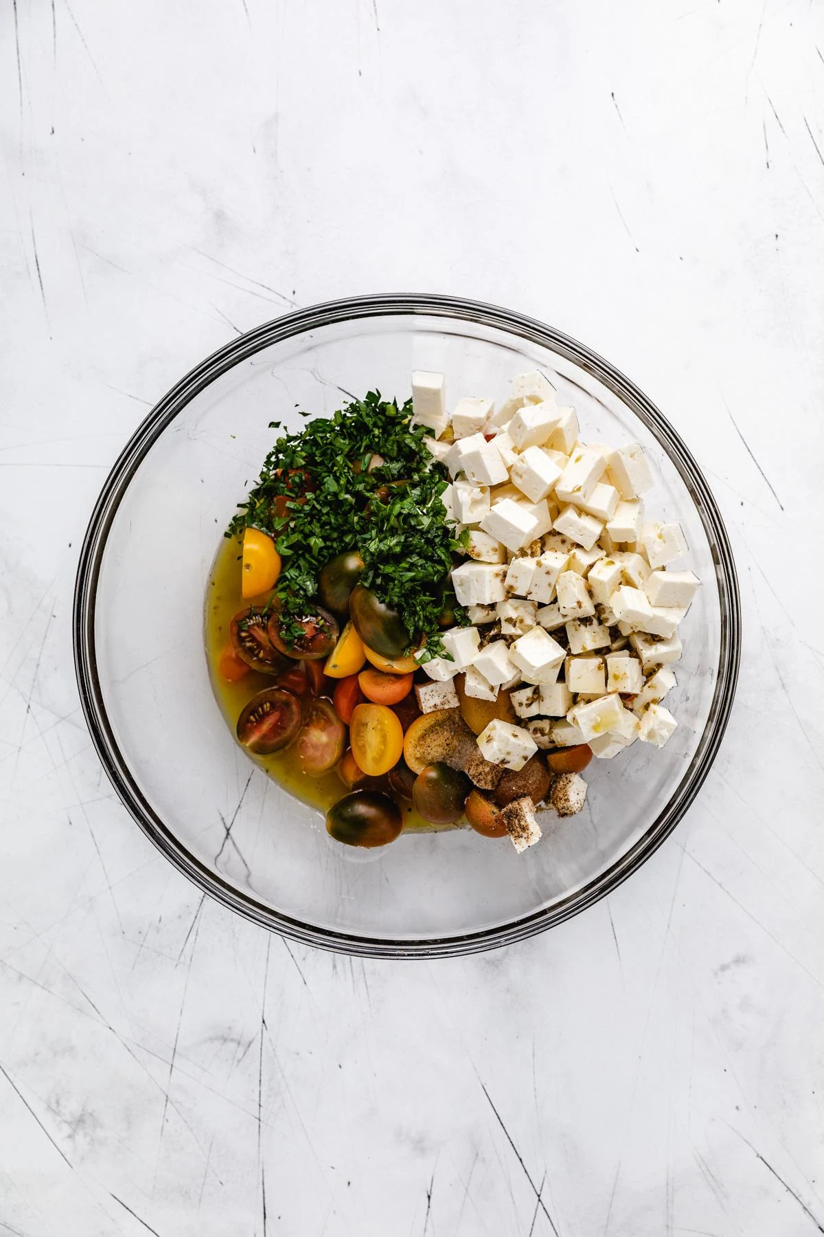 Vinaigrette dressing poured over a tomato and feta salad.
