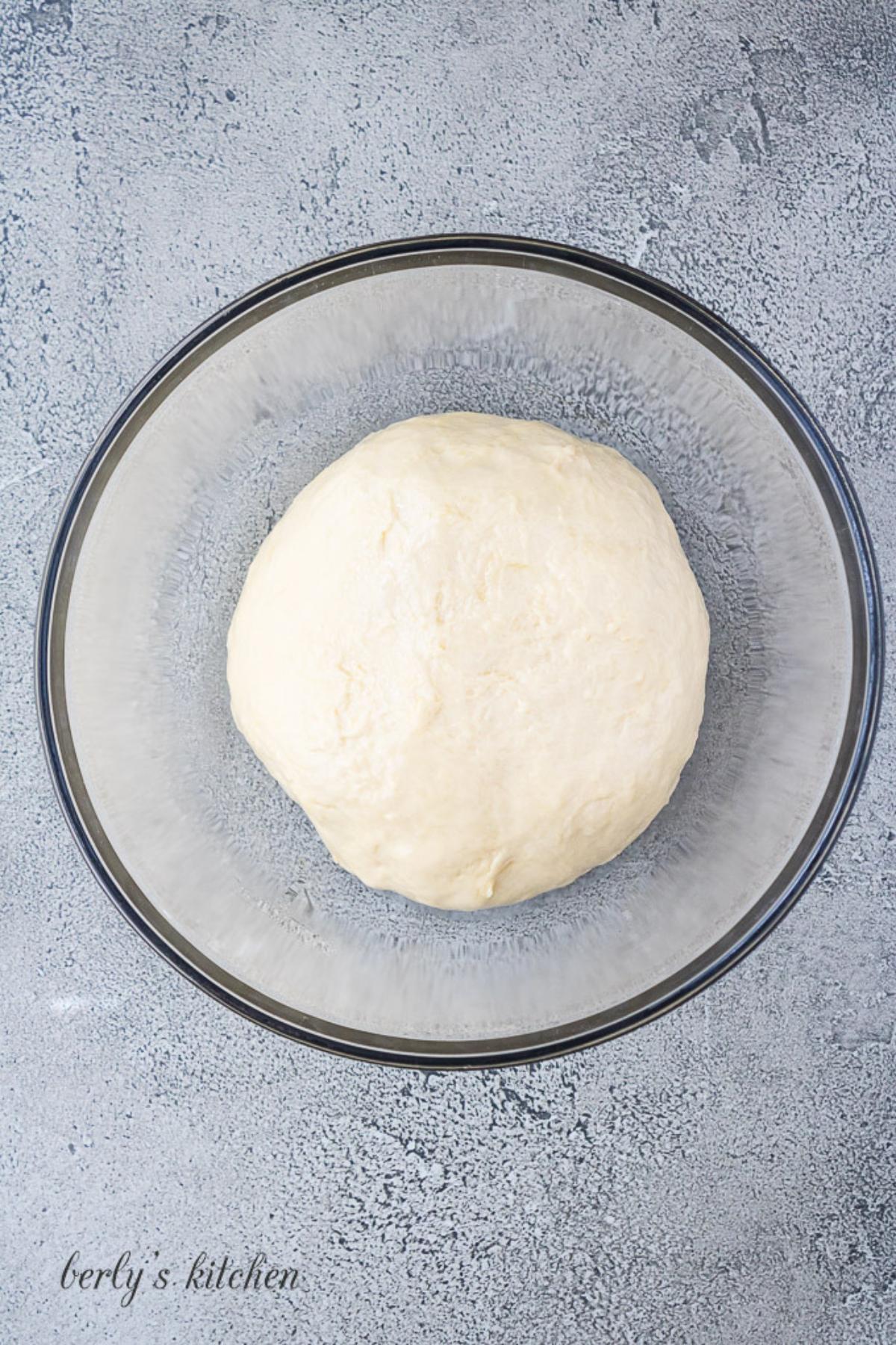 Ball of dough in a glass bowl.