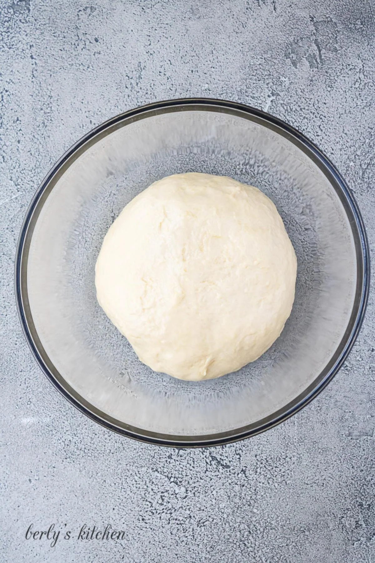 Ball of dough in a glass bowl.