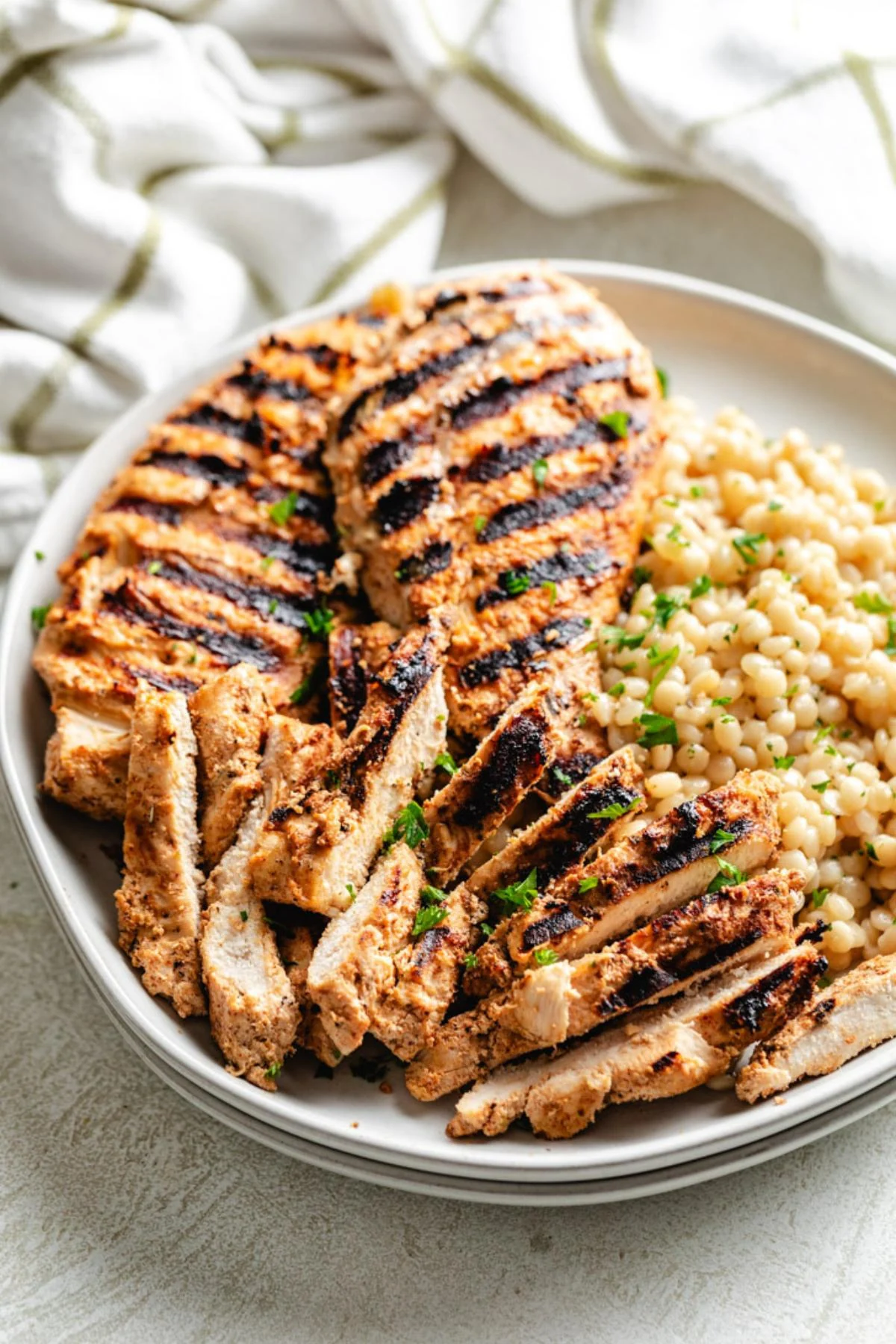 Greek yogurt marinated chicken next to pearled couscous.