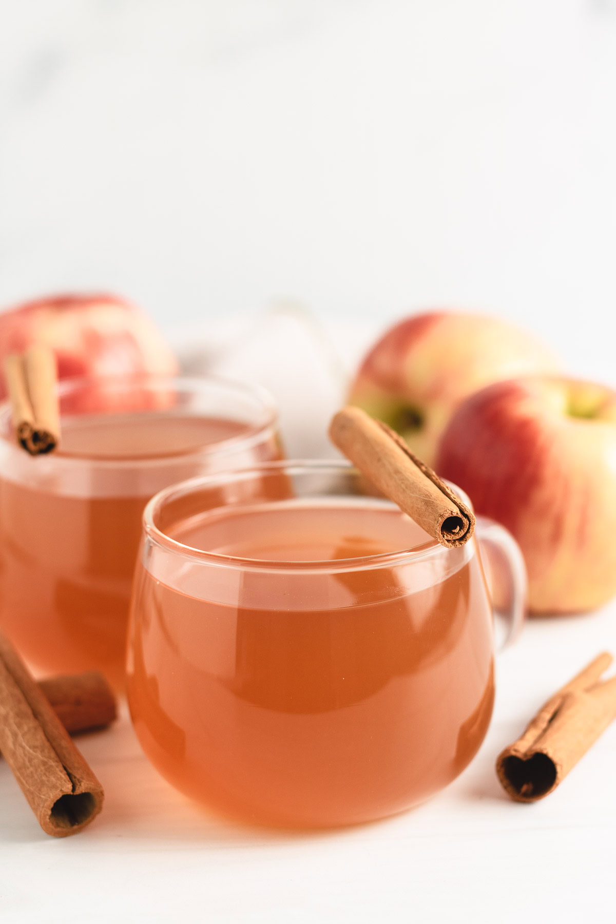 Glasses of homemade apple cider with cinnamon sticks.