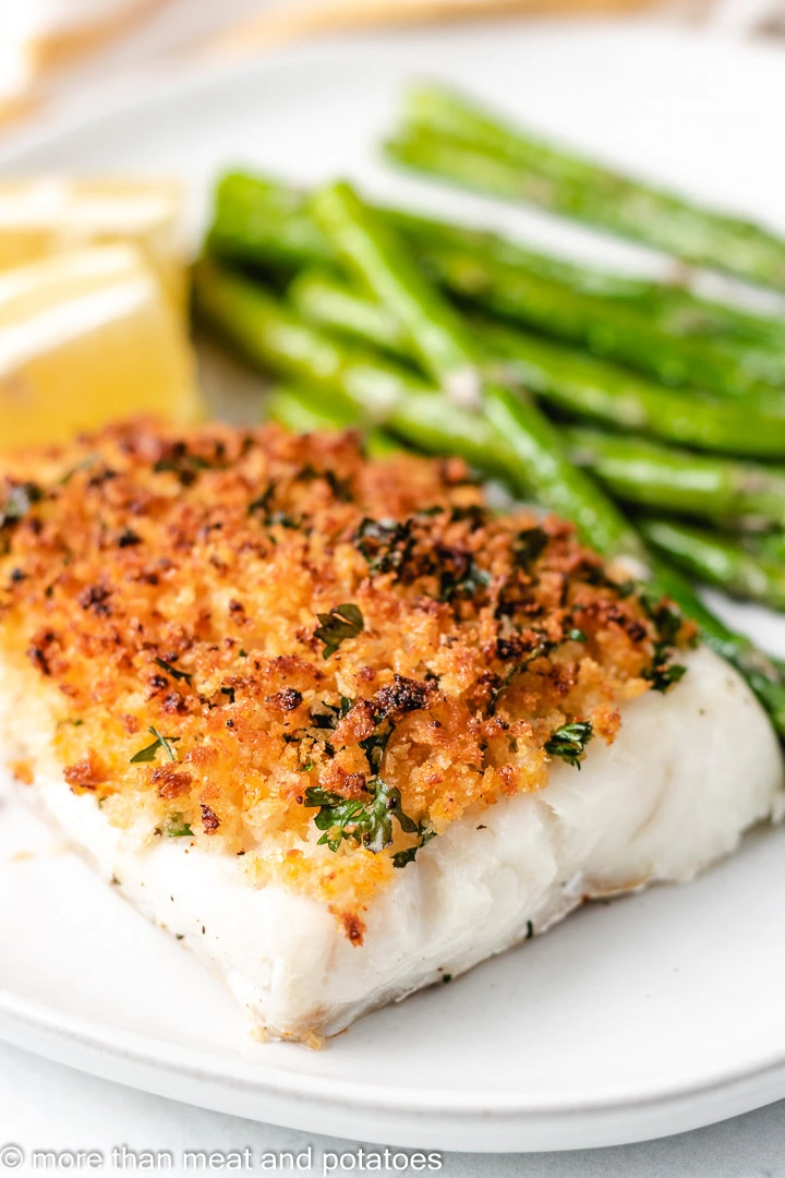 Piece of baked cod with panko on a white plate.