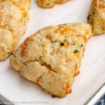 Soft, cheesy, cheddar chive scones on a baking sheet.