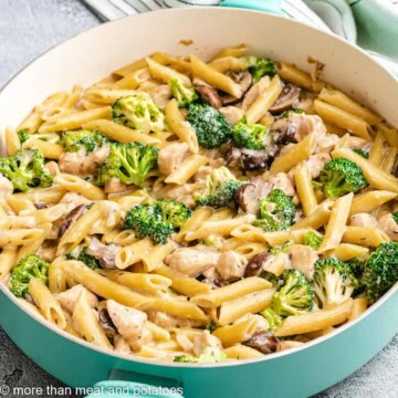 Teal pan filled with chicken mushroom broccoli pasta.