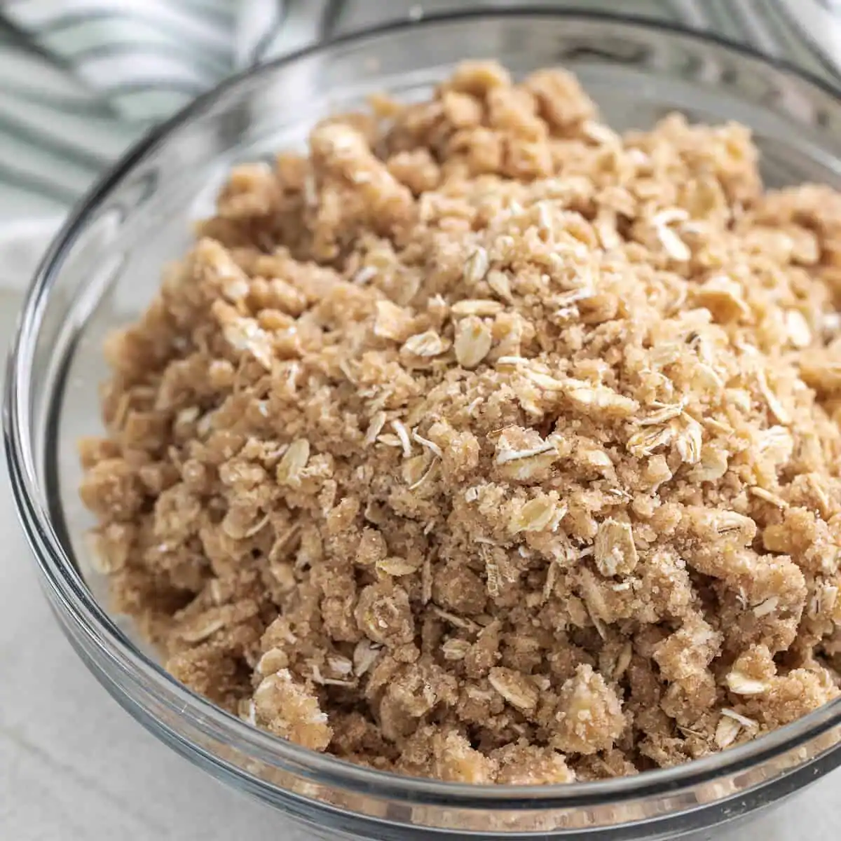 Glass bowl filled with crumble topping with oats.