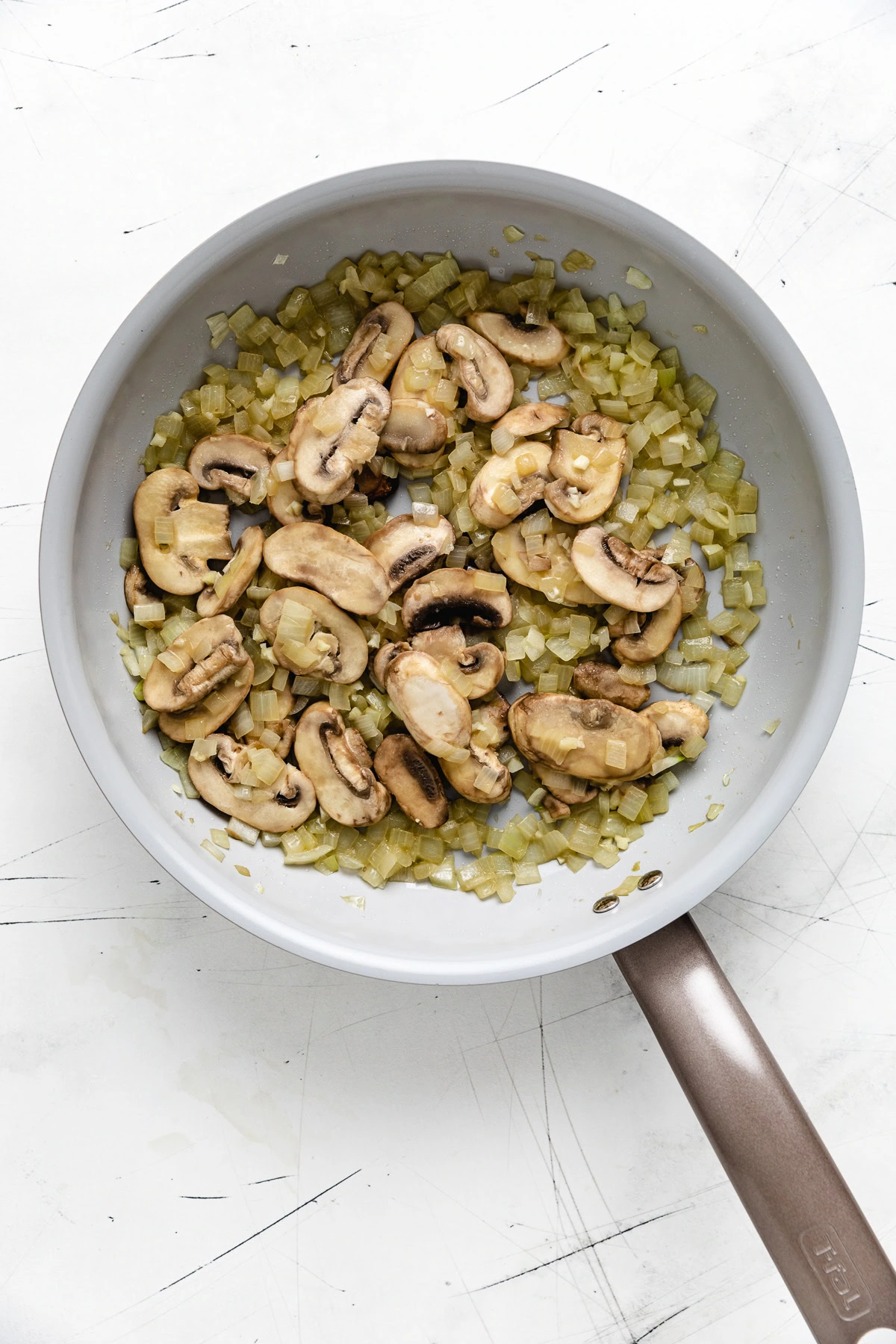 Sautéed mushrooms and diced onions in a skillet.