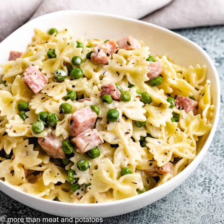 White bowl filled with ham and peas pasta.