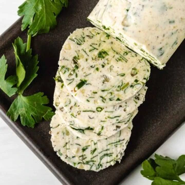 Overhead view of sliced garlic herb butter on a platter.