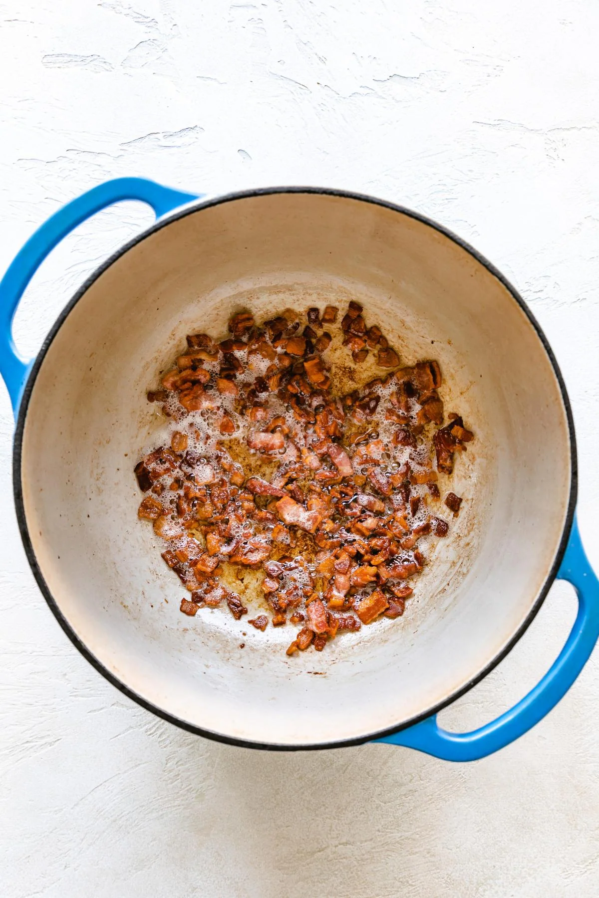 Crumbled bacon cooking in a Dutch oven.