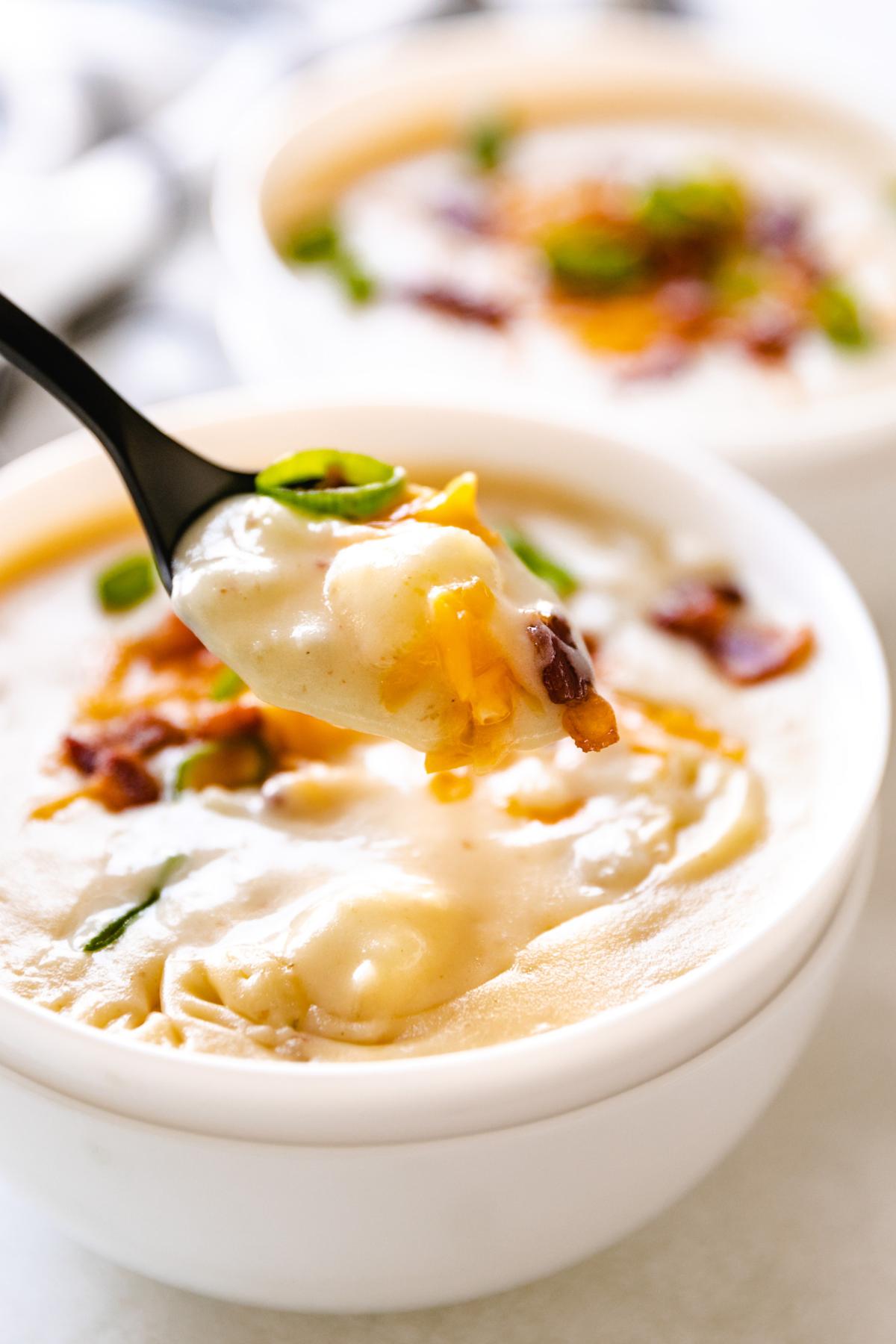 Spoon holding up a bowl of potato soup.