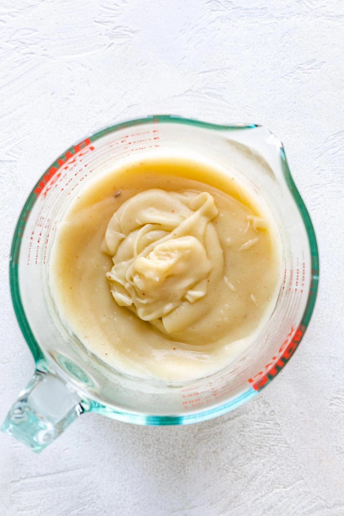 Overhead view of mashed potatoes in a measuring cup.
