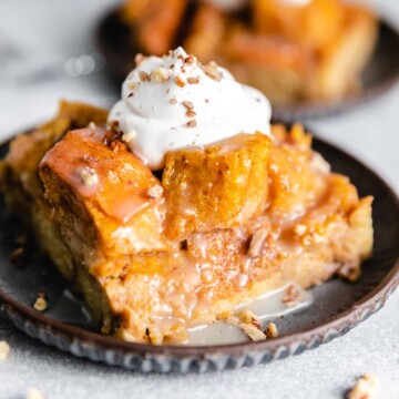 Slice of pumpkin bread pudding on a plate with whipped cream.