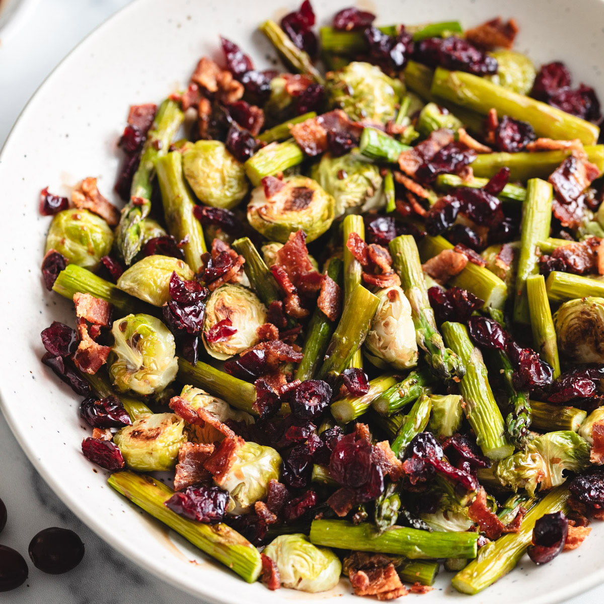 Close up view of a bowl filled with roasted asparagus and brussels sprouts.