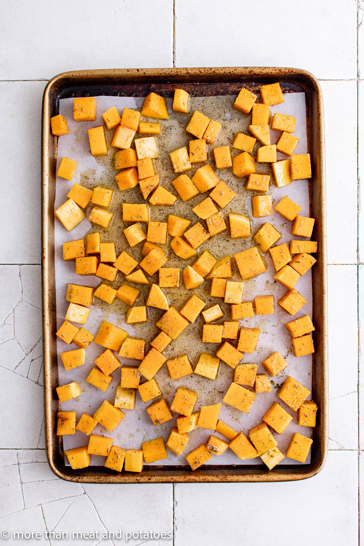 Raw butternut squash arranged on a sheet pan.