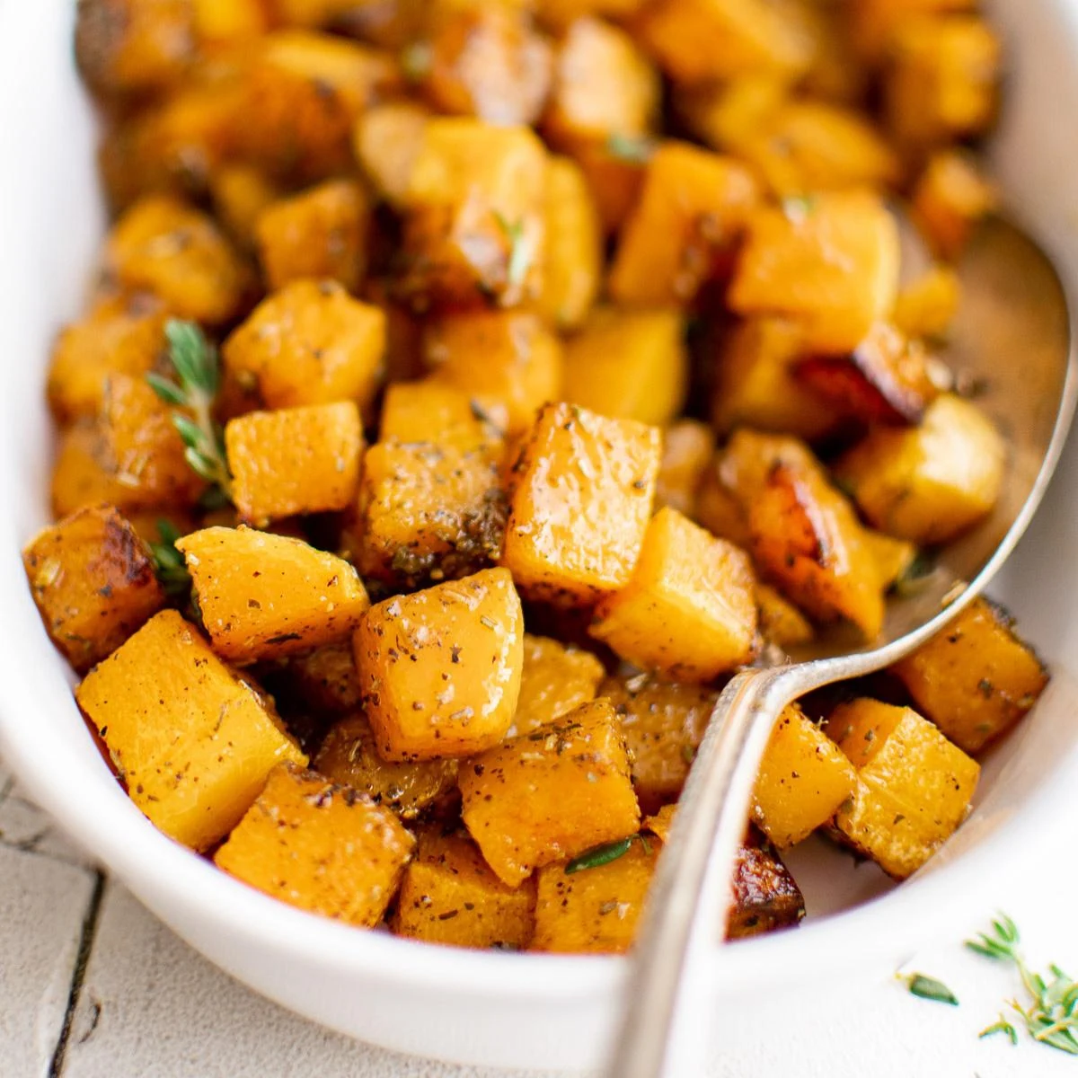 Close up view of roasted butternut squash in a white serving dish.
