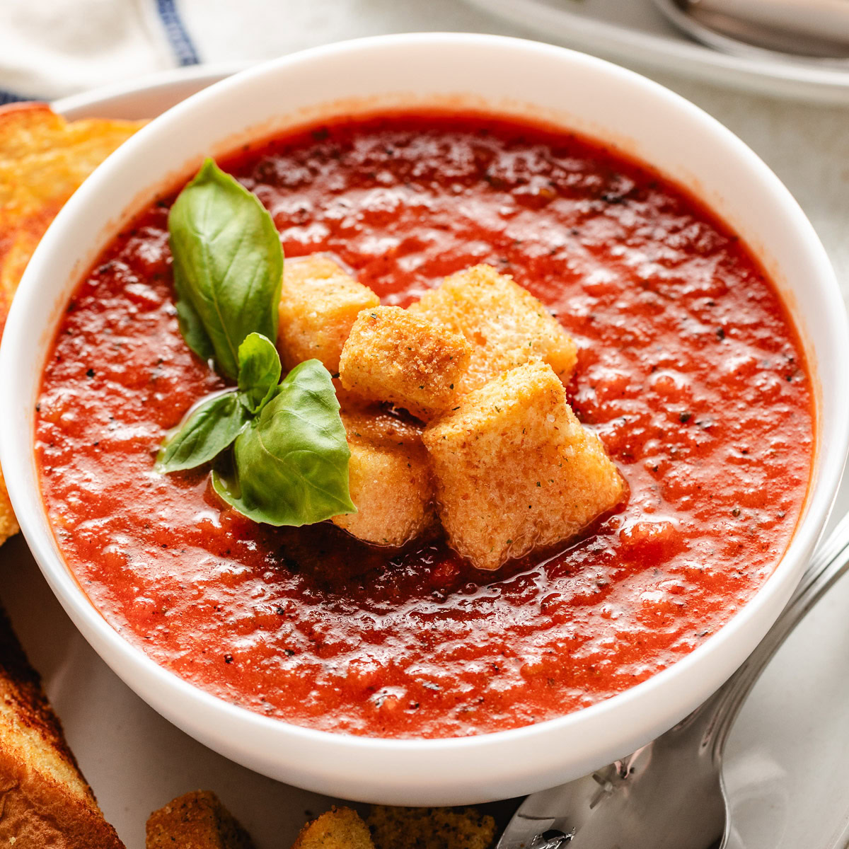 Close up view of tomato basil soup with croutons.