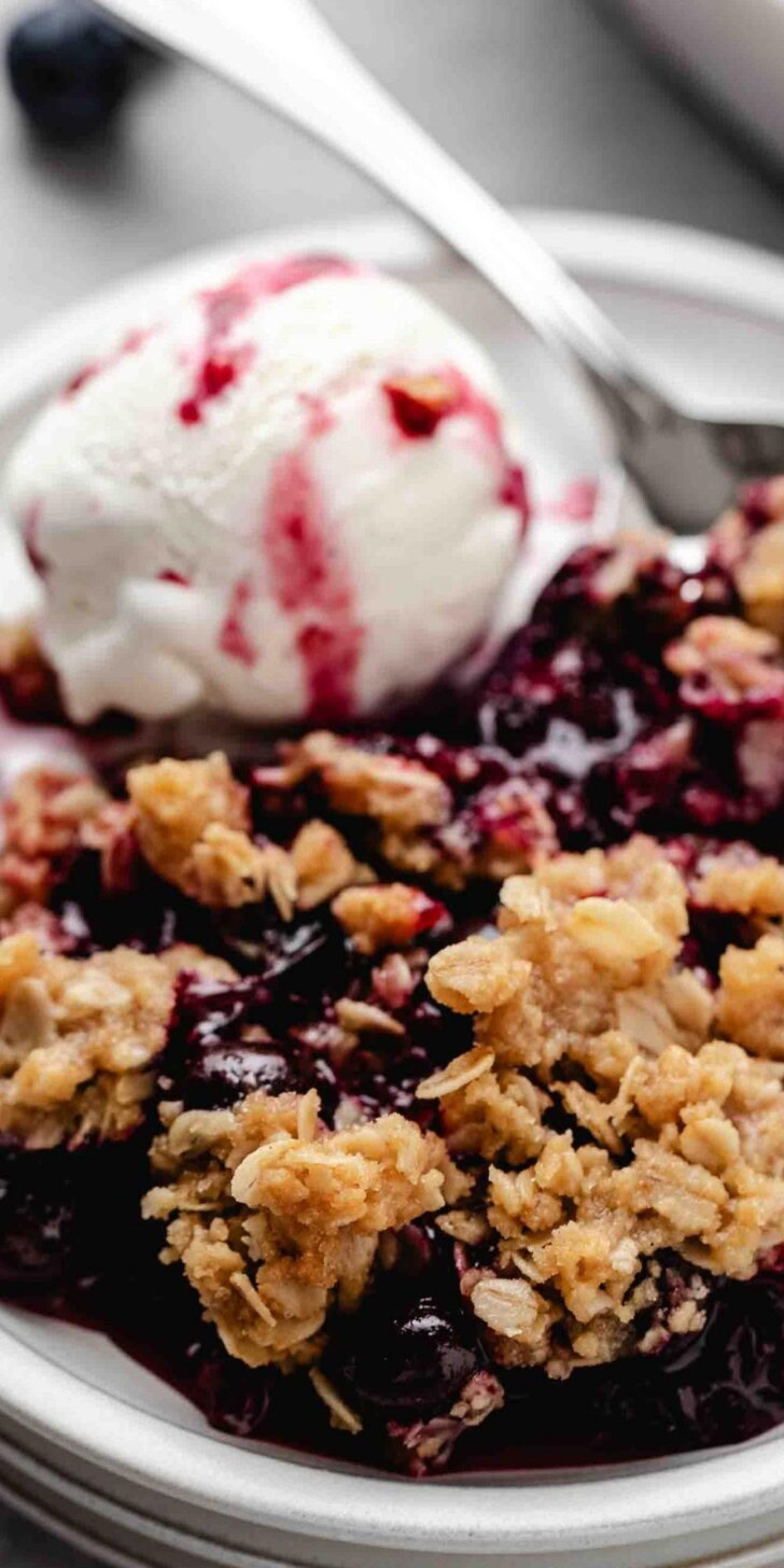 Close up view of blueberry crisp and ice cream on a plate.