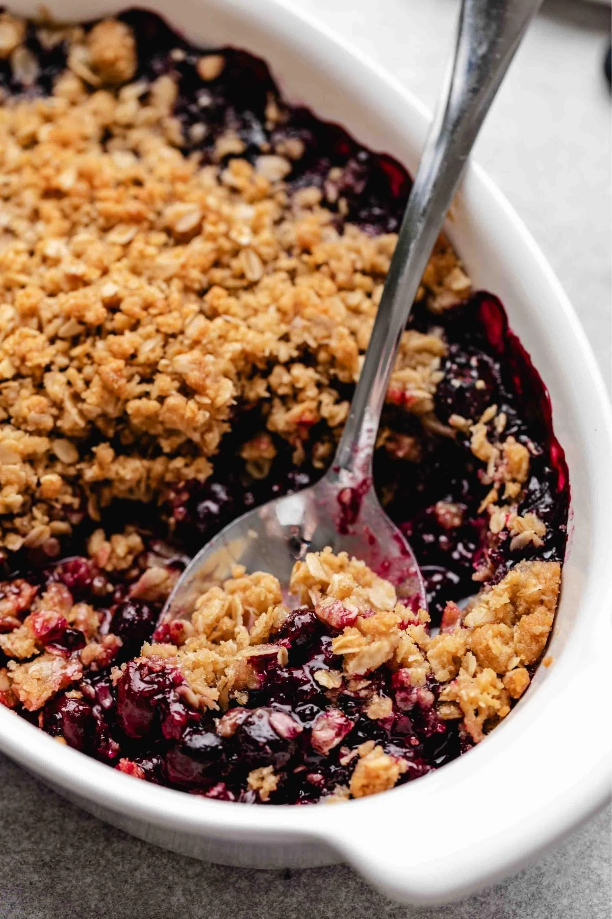 Spoonful of blueberry crisp in the baking dish.