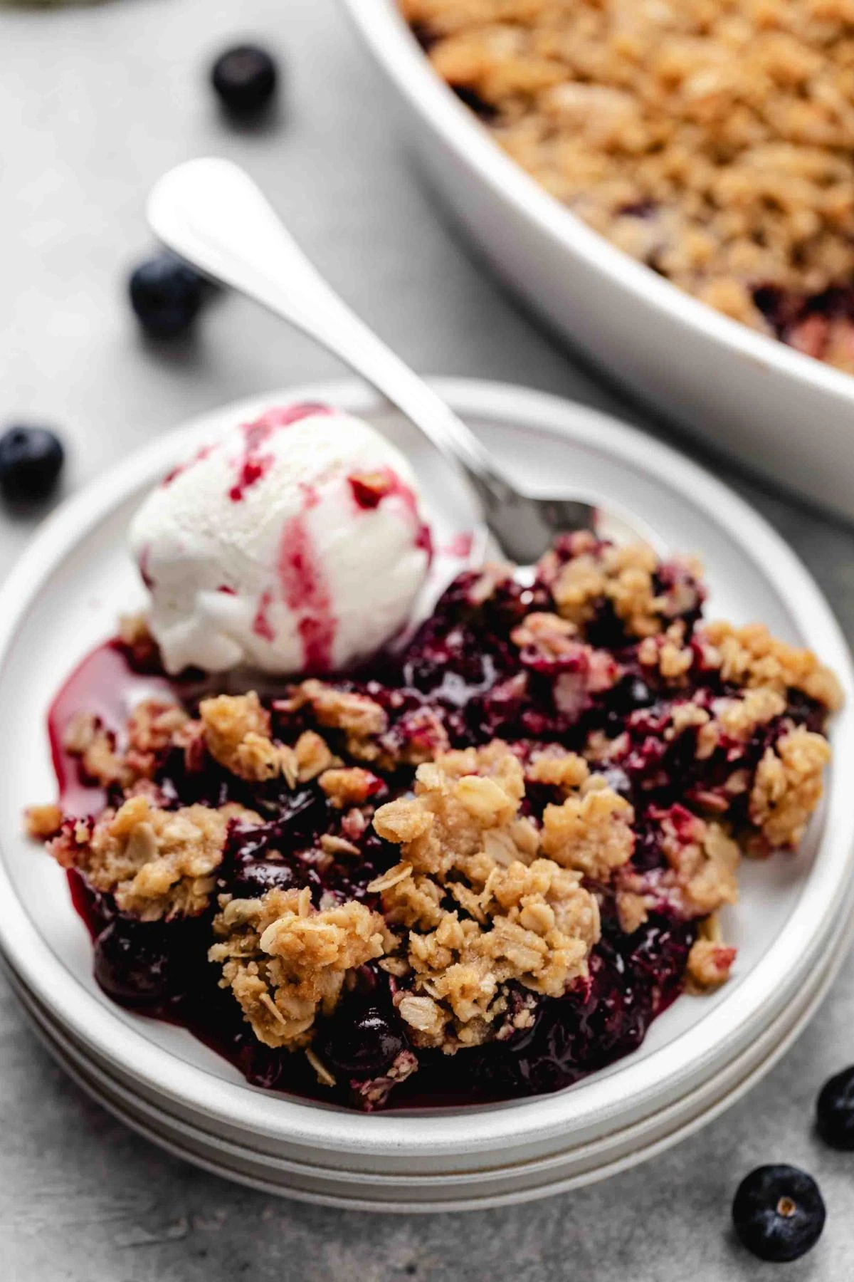 Close-up of blueberry crisp with oat topping and ice cream.
