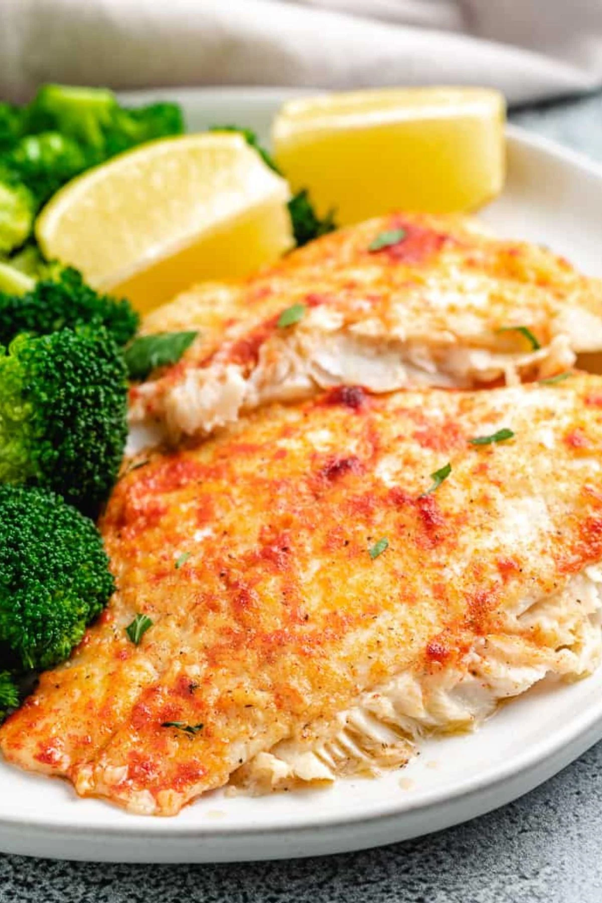 Baked flounder fillets on a light colored plate.