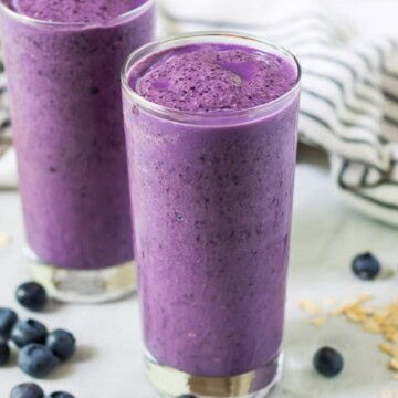 Creamy blueberry smoothie in a tall glass.
