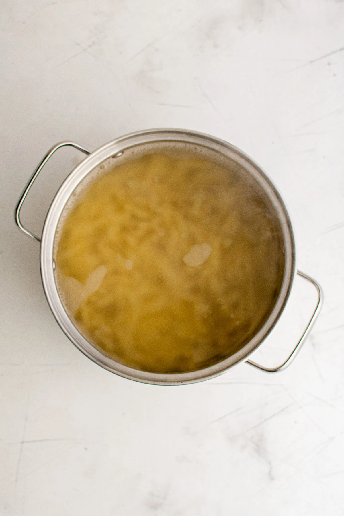 Penne noodles in a pan of water.