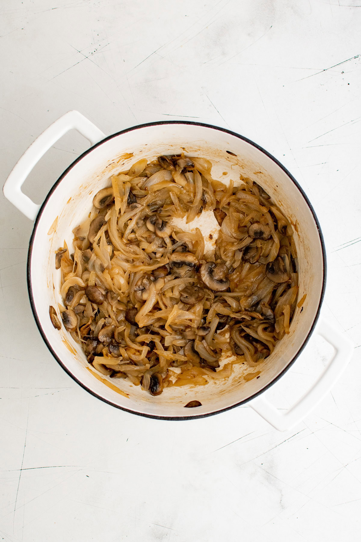 Caramelized onions and baby bella mushrooms in a pan.