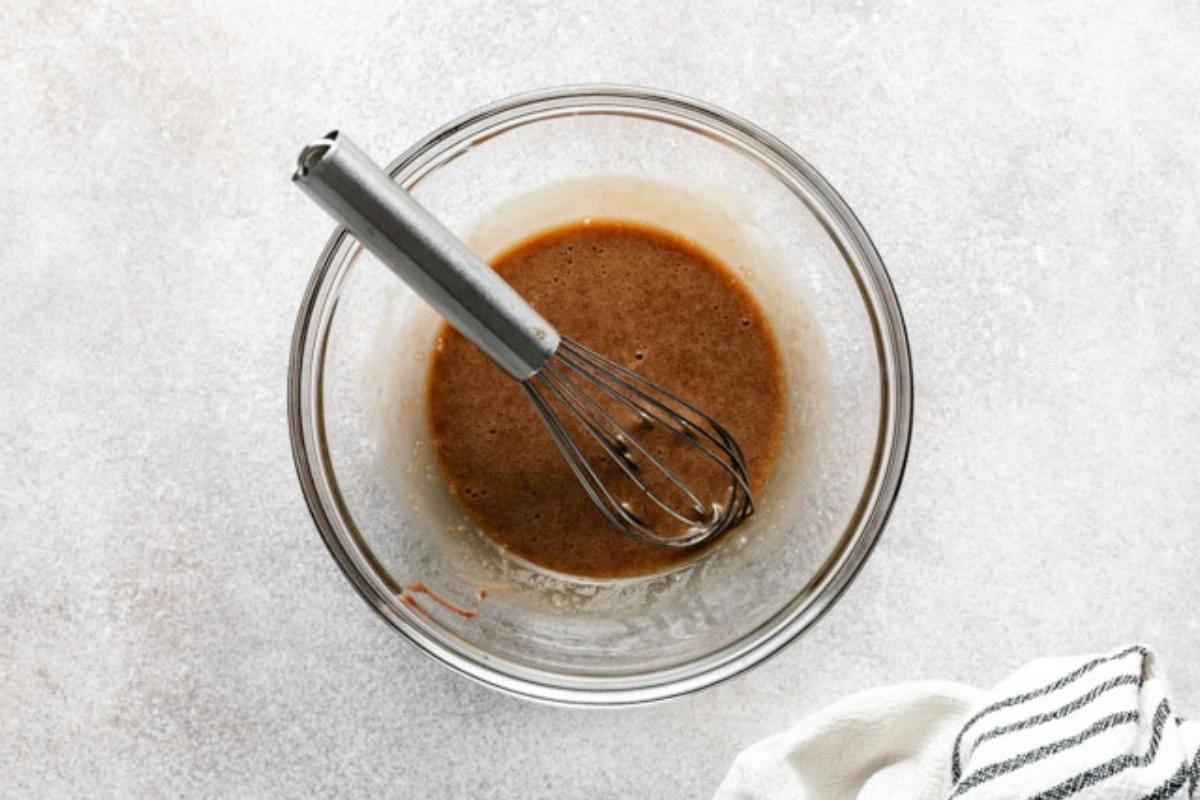 Egg yolks tempered in a bowl with chocolate pudding liquid.