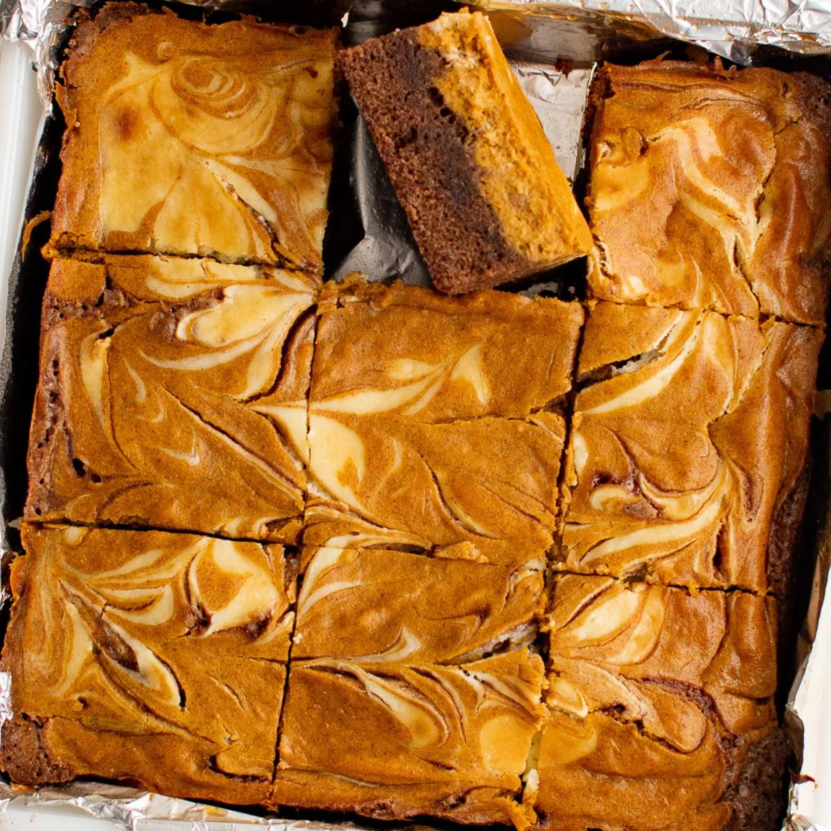 Overhead view of a pan of swirled pumpkin cheesecake brownies.