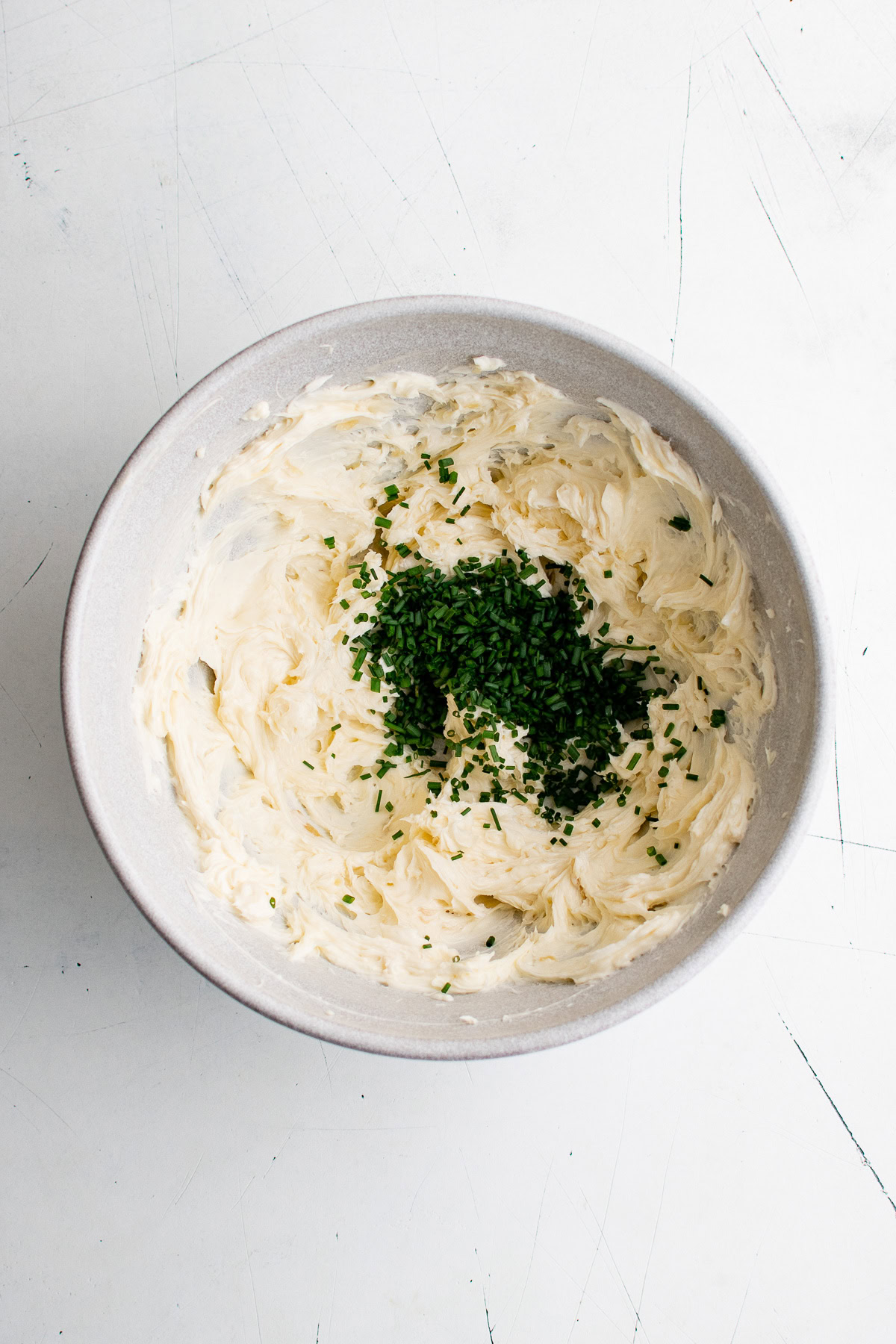 Chopped chives added to a bowl of garlic butter.