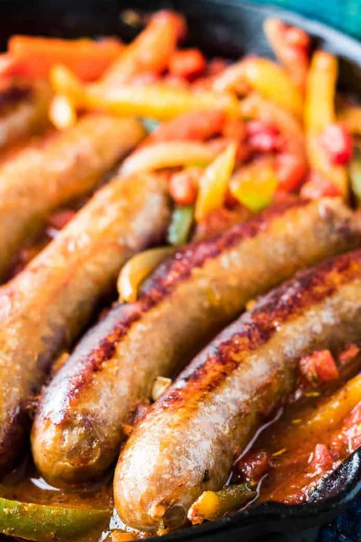 Italian sausage links, peppers, and onions in a cast iron pan.
