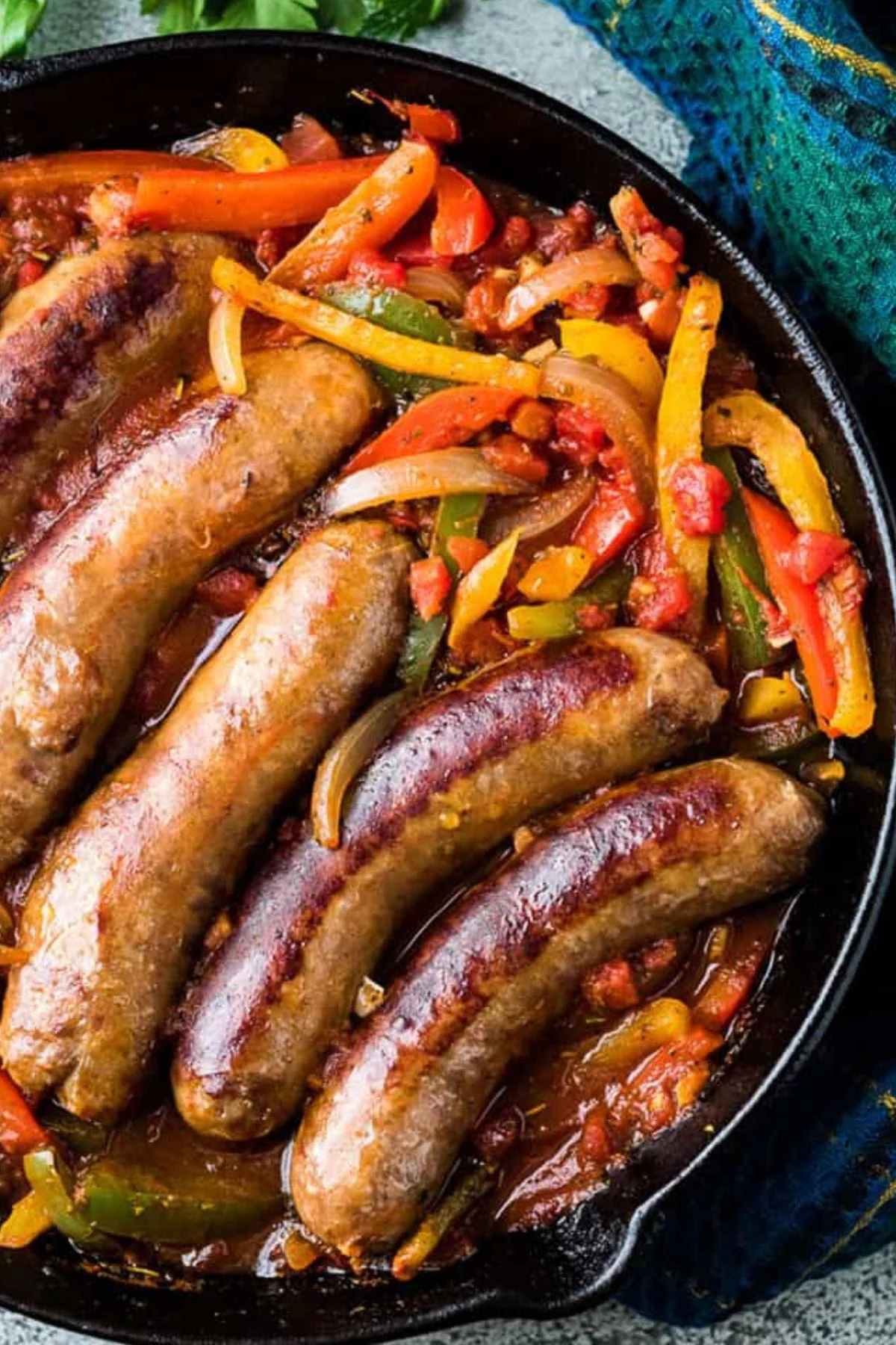 Overhead view of sausage and peppers in cast iron.